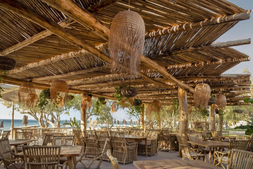 Une terrasse ombragée avec des tables et des chaises en bois face à la mer.