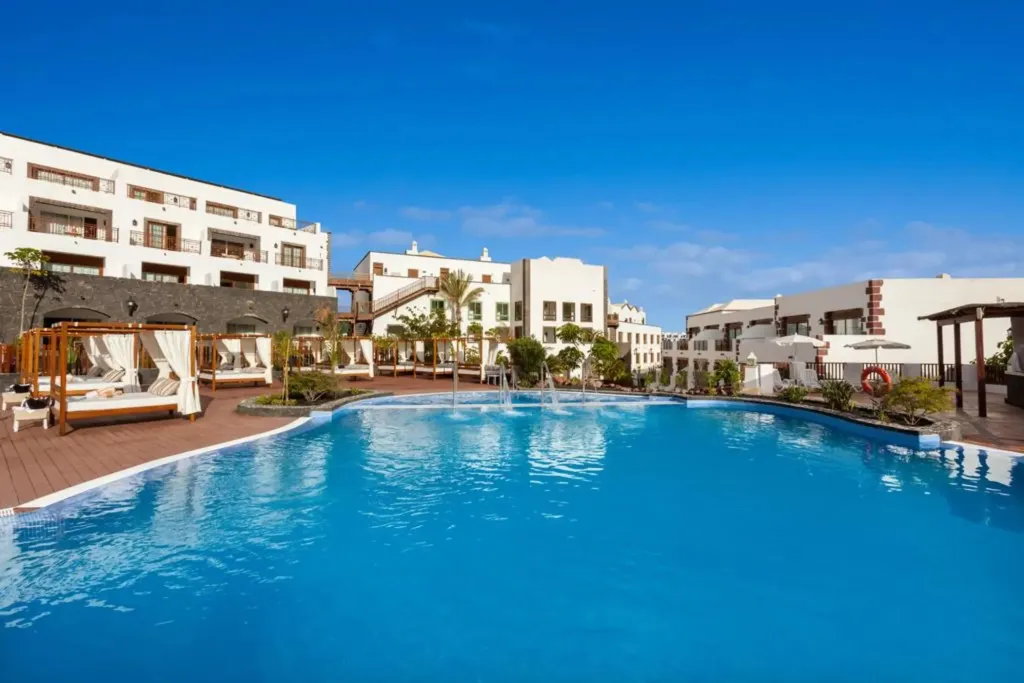 Une piscine turquoise bordée d'une terrasse ensoleillée avec des cabanas.