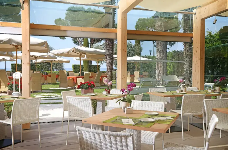 Une salle à manger lumineuse avec des tables dressées et une vue sur un jardin verdoyant.