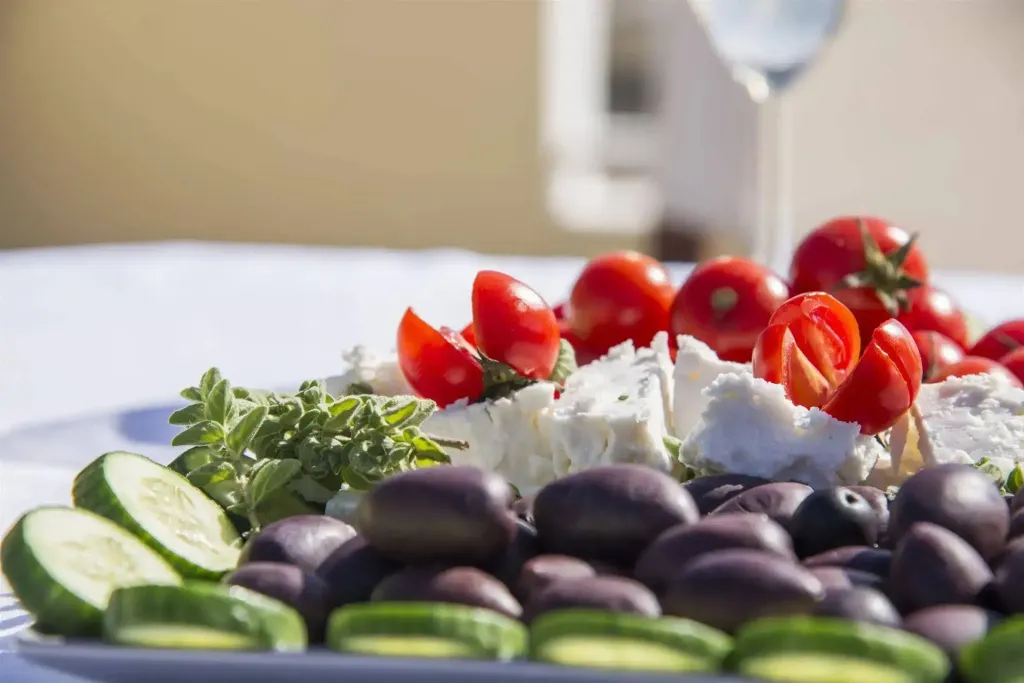 Assiette de crudités et de fromage frais, décorée de tomates cerises et d'olives.