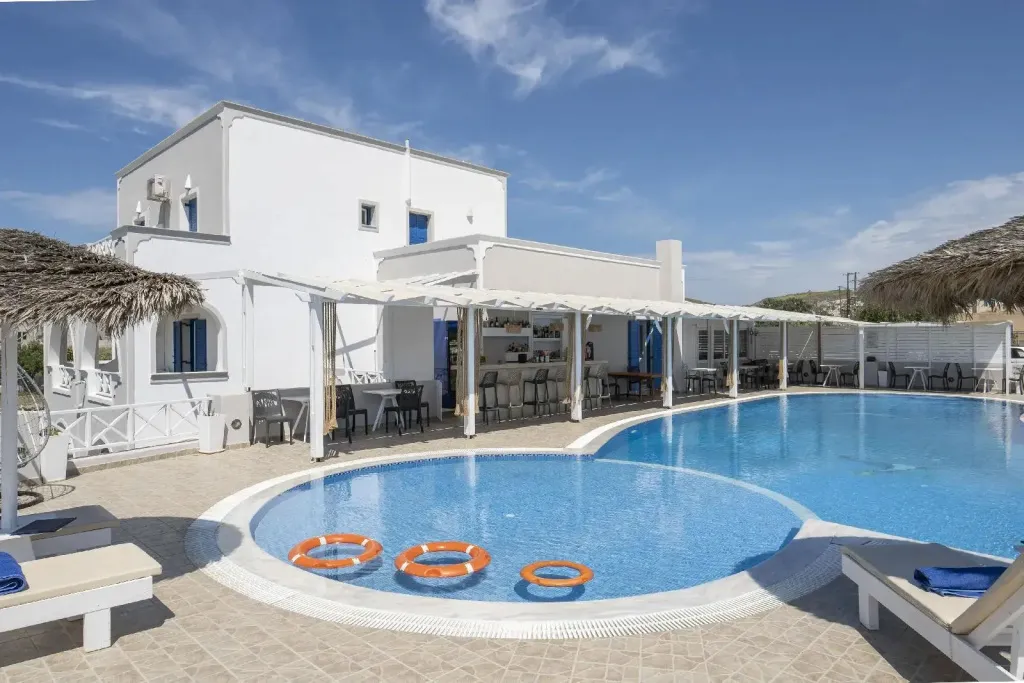 Bâtiment blanc avec piscine et espace bar ombragé.