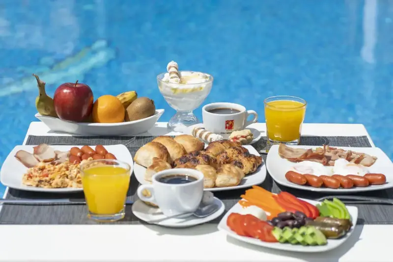 Un plateau de petit-déjeuner copieux est présenté sur une table près d'une piscine.