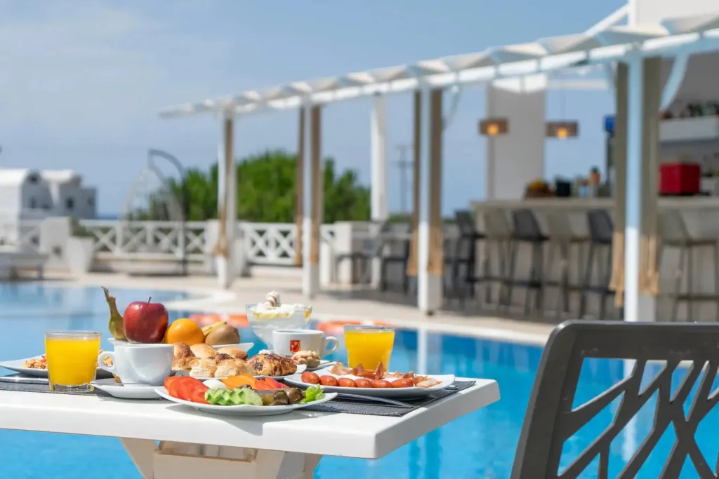 Une table est dressée avec un petit-déjeuner face à une piscine.