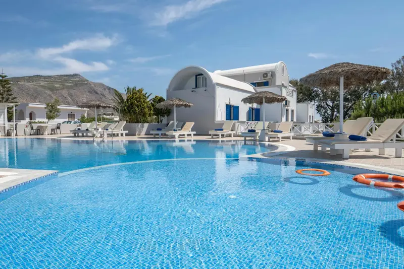 Piscine bleue entourée de chaises longues blanches sous des parasols.
