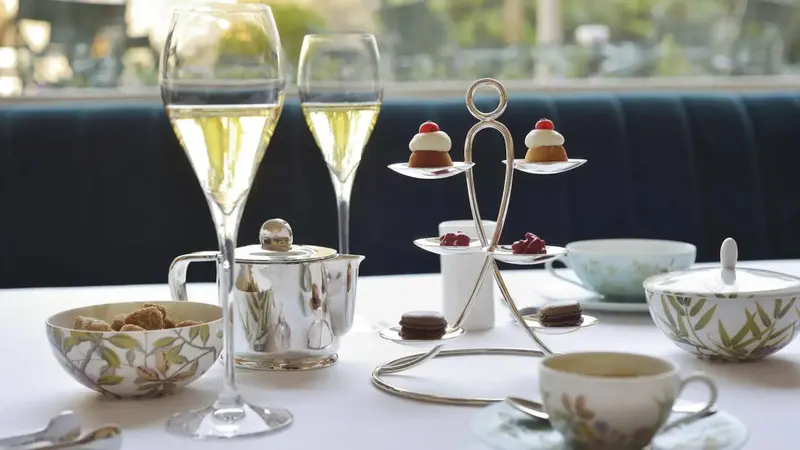 Une table est dressée avec des boissons, une théière et des pâtisseries.