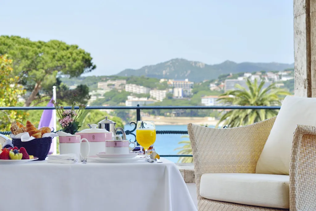 Une table dressée pour le petit-déjeuner offre une vue sur la mer et les collines environnantes.