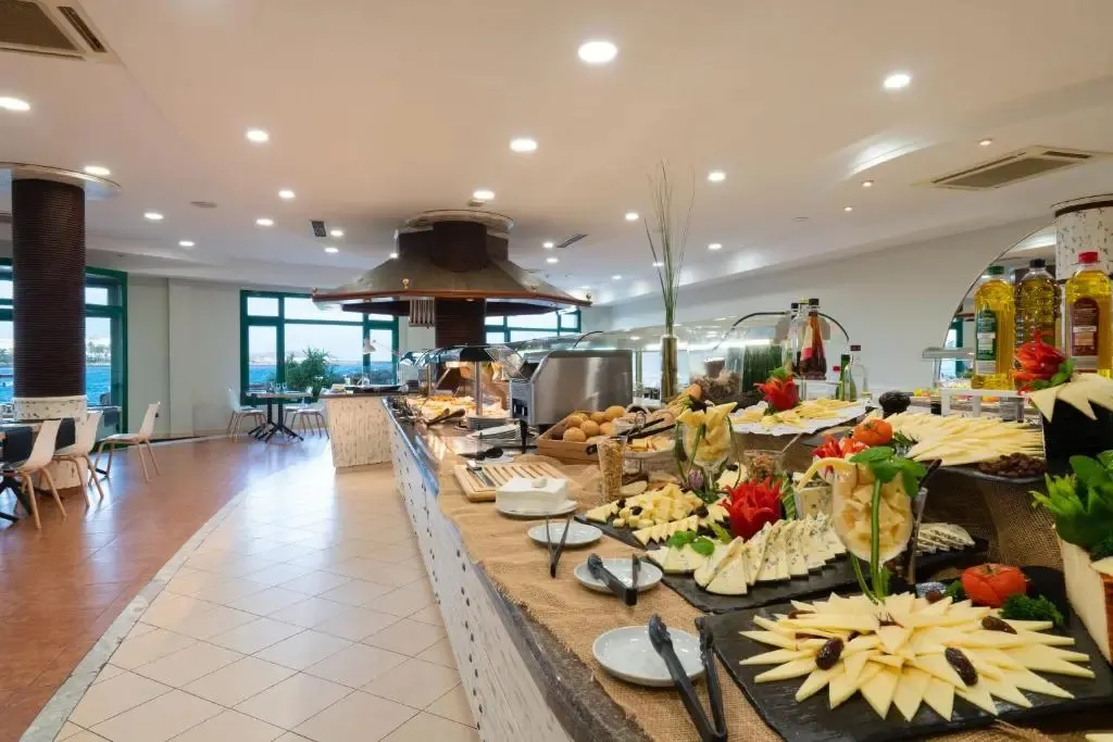 Un buffet garni de fromages et de charcuteries est présenté dans une salle lumineuse.