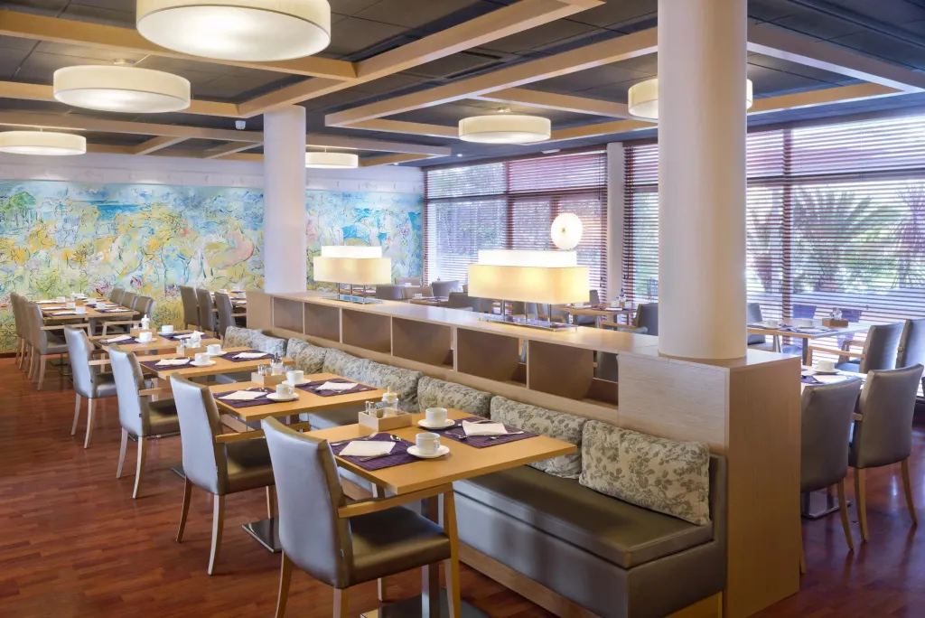 Une salle lumineuse avec des tables dressées pour le repas.