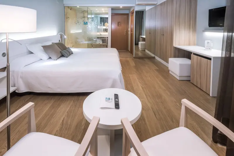 Une chambre lumineuse avec un grand lit et un espace détente.