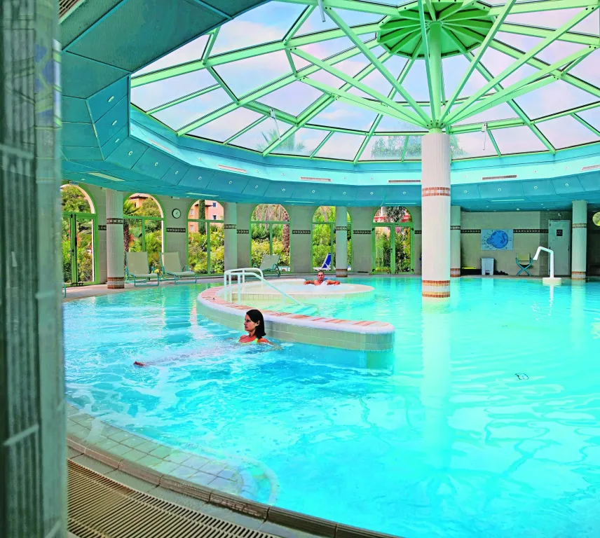 Une piscine intérieure lumineuse avec des nageurs et un espace de détente.