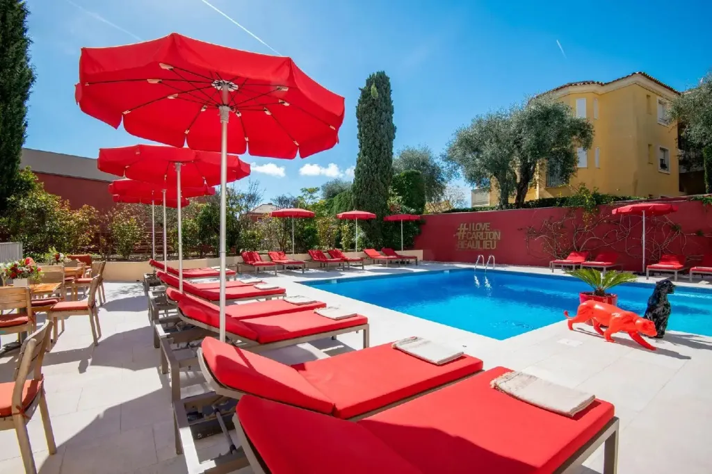 Transats rouges disposés autour d'une piscine ensoleillée sous des parasols.