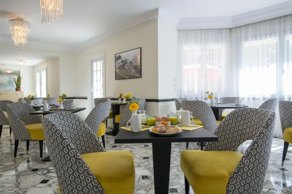 Une salle lumineuse avec des tables dressées pour le petit-déjeuner.