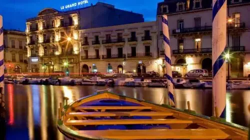 Un bateau amarré sur un canal urbain au crépuscule, avec des bâtiments illuminés en arrière-plan.