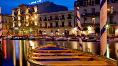 Un bateau amarré sur un canal urbain au crépuscule, avec des bâtiments illuminés en arrière-plan.