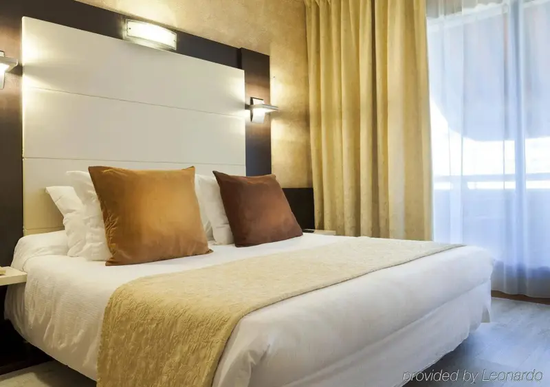 Une chambre lumineuse avec un grand lit recouvert d'une courtepointe et de coussins.