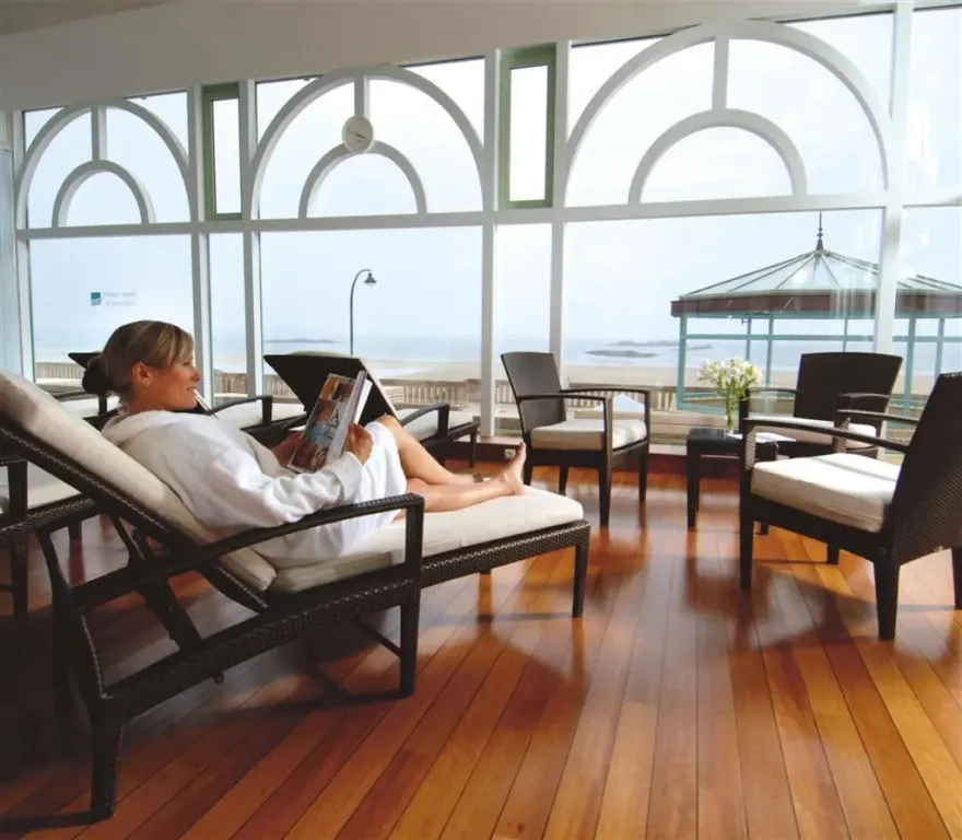 Une personne se relaxe sur une chaise longue dans un espace lumineux avec vue sur la mer.