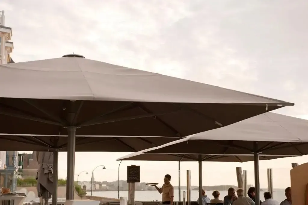 Une terrasse ombragée avec des parasols et des clients attablés.
