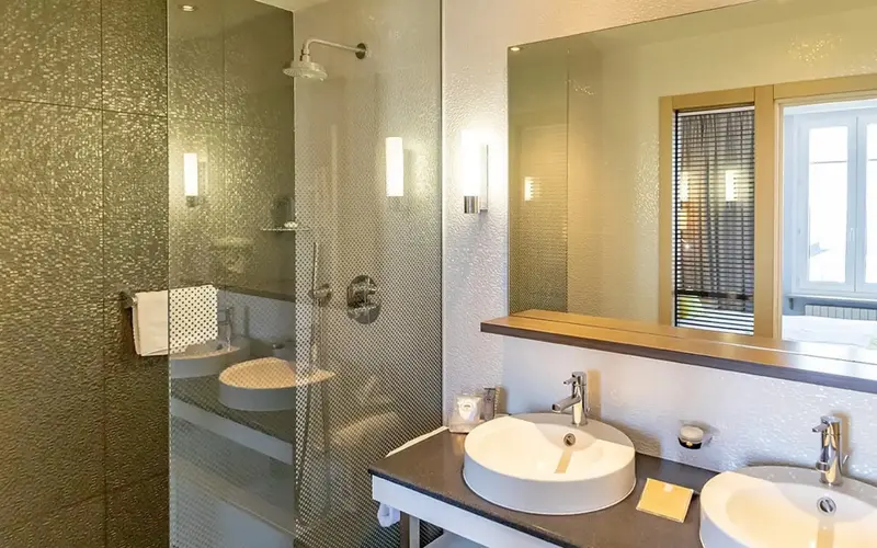 Une salle de bain moderne avec douche à l'italienne et deux vasques.