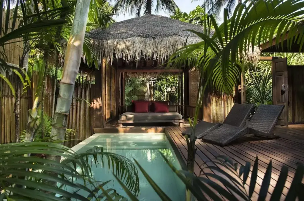 Un espace de détente extérieur avec une petite piscine et un salon ombragé.