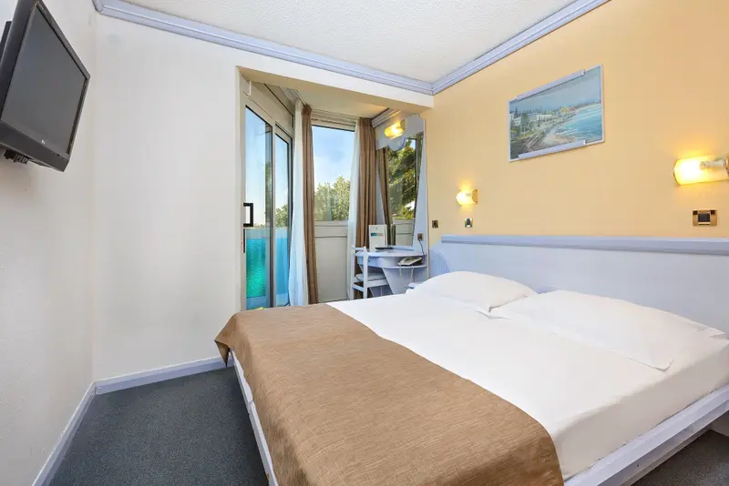 Une chambre lumineuse avec un lit double et un balcon.