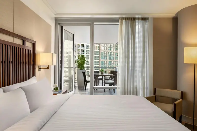 Une chambre lumineuse avec un lit blanc et un accès à un balcon.