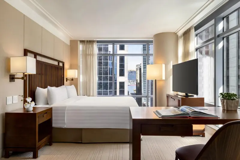 Une chambre lumineuse avec un grand lit et un bureau près d'une fenêtre.