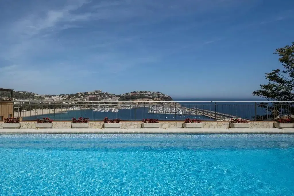 Une piscine turquoise surplombe un port de plaisance ensoleillé.