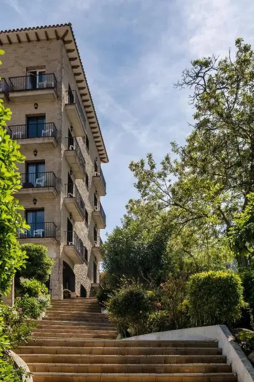 Bâtiment à plusieurs étages avec des balcons et un escalier montant vers l'entrée.