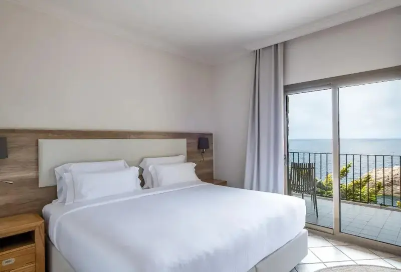 Une chambre lumineuse avec un grand lit donnant sur la mer.