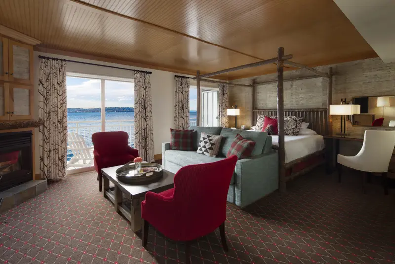Une chambre lumineuse avec un lit à baldaquin et un coin salon donnant sur la mer.