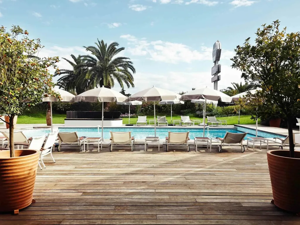 Terrasse en bois avec transats et parasols donnant sur une piscine.