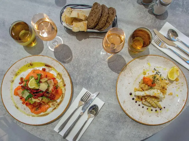 Une table est dressée avec des plats de poisson et des verres de vin.