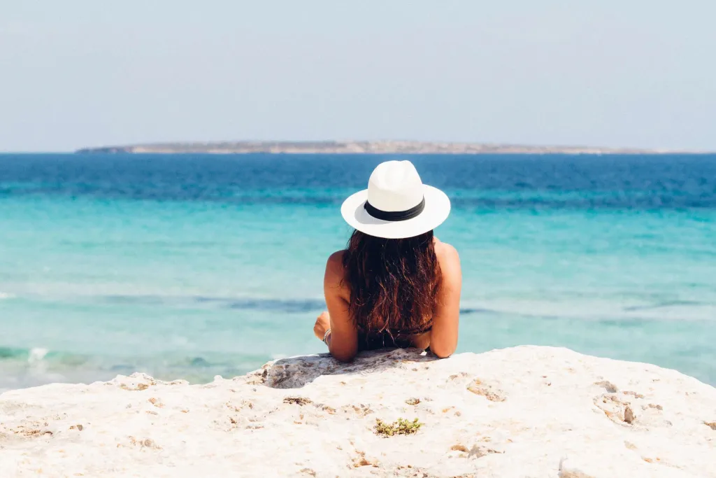 Une personne est allongée sur un rocher face à la mer.