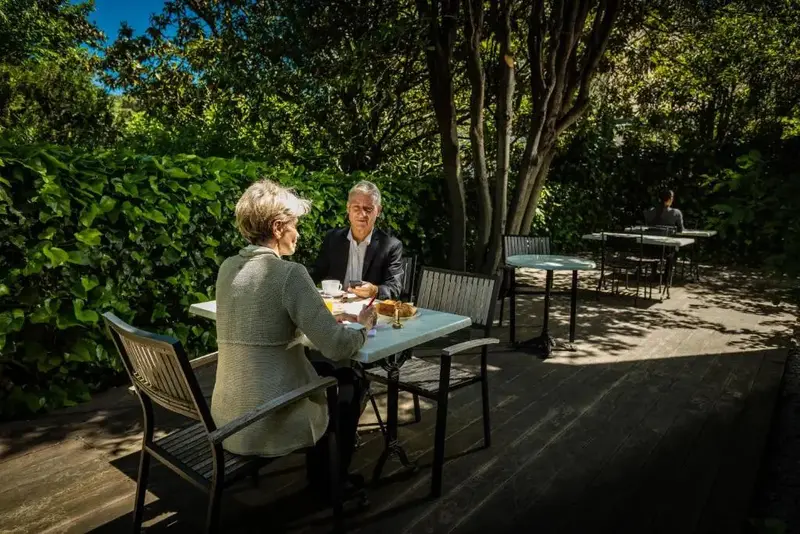 Deux personnes sont assises à une table en terrasse, profitant d'un moment de détente.