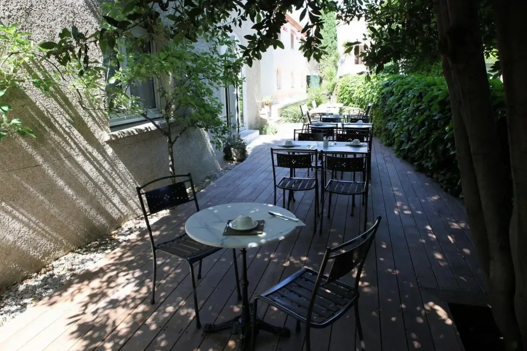 Terrasse ombragée avec tables et chaises pour les repas.