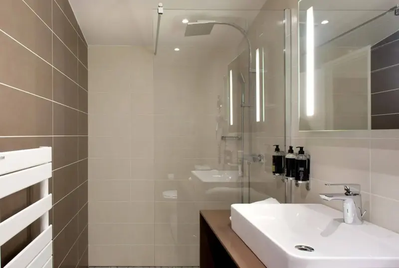 Une salle de bain moderne avec douche à l'italienne et vasque blanche.