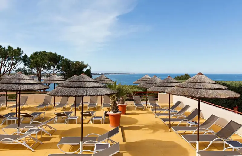Terrasse aménagée avec transats et parasols offrant une vue sur la mer.