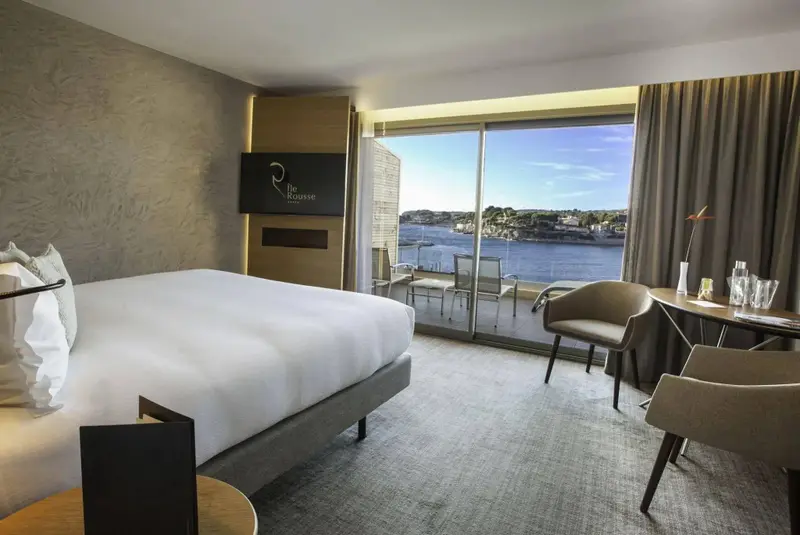 Une chambre lumineuse avec un grand lit et un accès à une terrasse vue sur mer.