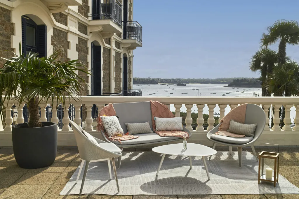 Mobilier d'extérieur sur une terrasse avec vue sur la mer et des bateaux.