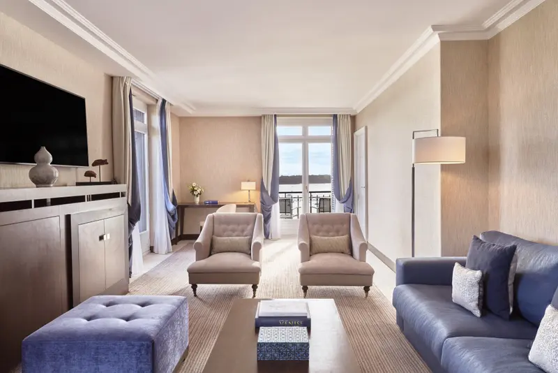 Un salon lumineux avec canapé, fauteuils et vue sur un paysage.