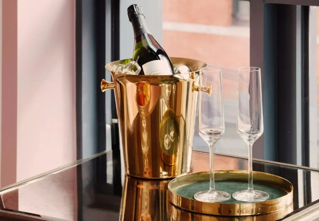 Une bouteille de champagne et deux flûtes sur un plateau doré.