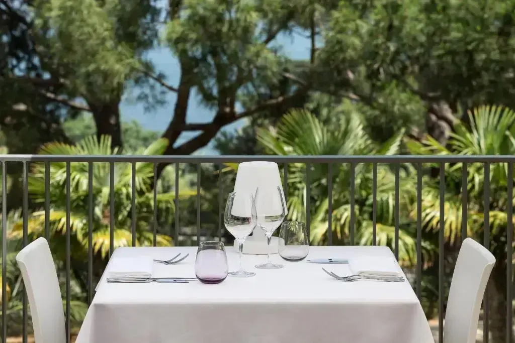 Table dressée sur une terrasse ombragée avec vue sur la végétation.