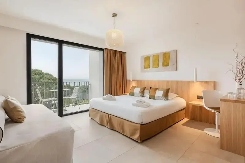 Une chambre lumineuse avec un grand lit et un accès à un balcon.