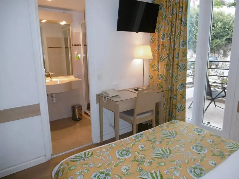 Une chambre lumineuse avec un bureau et un accès à un balcon.