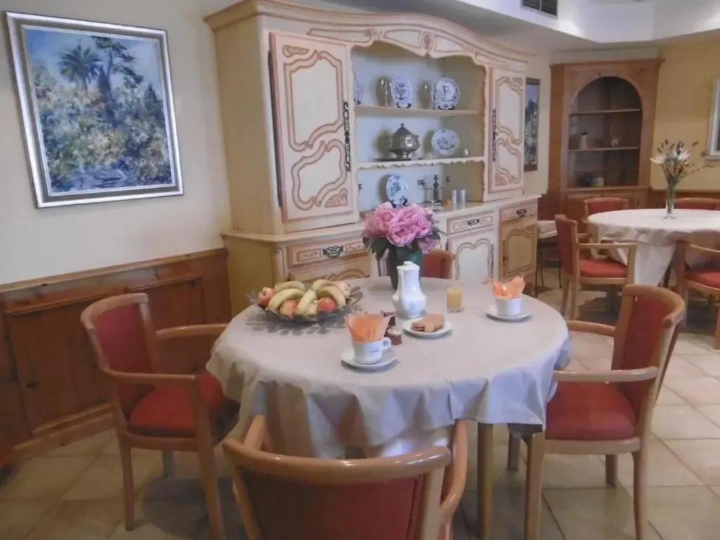 Une table ronde est dressée pour le petit-déjeuner dans une salle lumineuse.