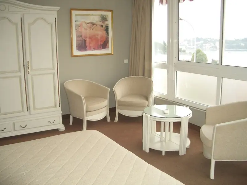 Une chambre lumineuse avec un coin salon et une vue sur la ville.