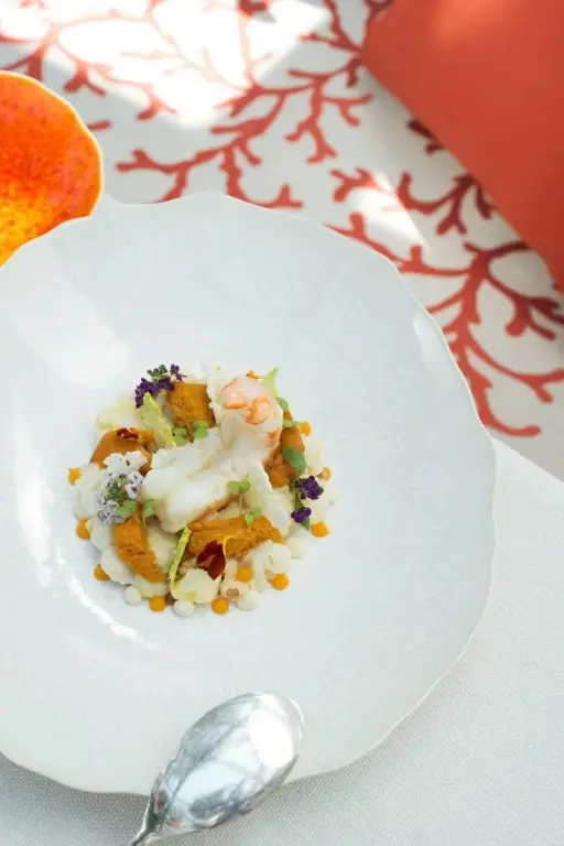 Assiette de fruits de mer décorée de fleurs et de sauce.