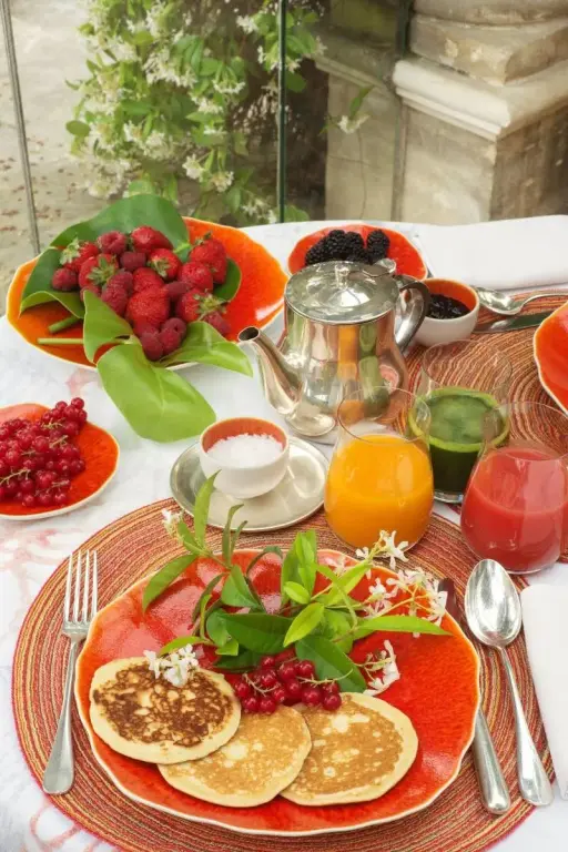 Une table est dressée avec des fruits frais, des crêpes et des boissons.