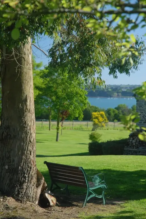 Un banc de parc en fer forgé se trouve sur une pelouse verdoyante avec vue sur la mer.