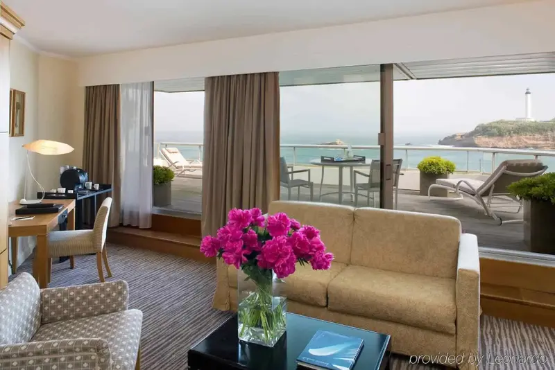 Un salon lumineux s'ouvre sur une terrasse avec vue sur la mer et un phare.